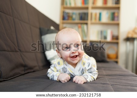 laughing baby on sofa, Beautiful smiling cute baby, expressive adorable happy child in child's room, blurry background