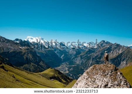 A hiker standing on the Bernese Oberland hiking ridge with mountain landscape in Switzerland Royalty-Free Stock Photo #2321233713