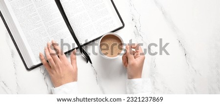 Female hands with Holy Bible and cup of coffee on light background with space for text, top view