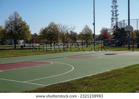 Outdoor basketball court in a park with a telephone cellular tower in the background