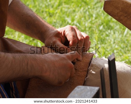 The gunsmith makes flint plates for the bolt of medieval firearms, hands and tools in close-up. Historical reconstruction of a military camp. Royalty-Free Stock Photo #2321241433