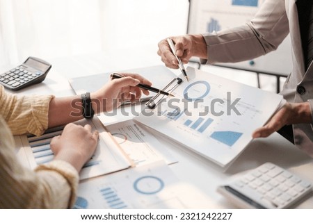 Team of two asian male and female business people working together discussing new financial graph data on office table with laptop and digital tablet.