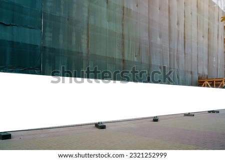 Blank long white hoarding with space for mockup information located in front of construction site with closed scaffold