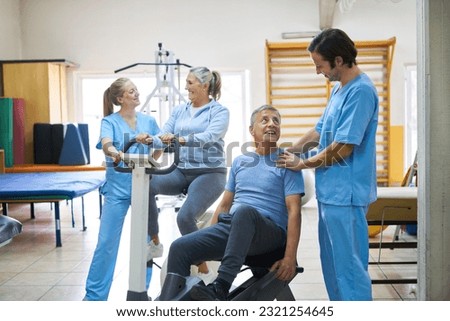 Therapists assisting happy senior man and woman exercising in rehabilitation center Royalty-Free Stock Photo #2321254645