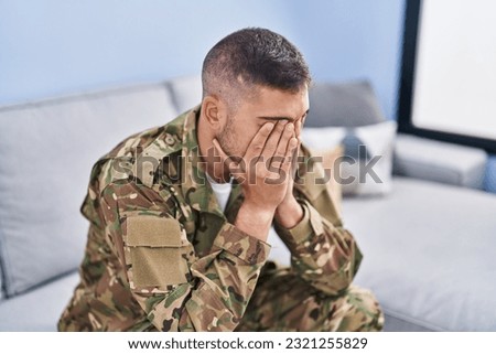 Young hispanic man army soldier sitting on sofa stressed at home