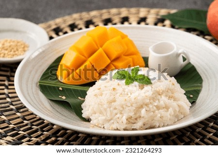 Delicious Thai mango sticky rice with cut fresh mango fruit in a plate on gray table background. Royalty-Free Stock Photo #2321264293