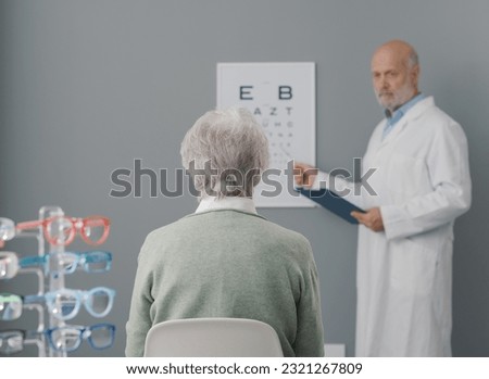 Senior woman having an eye exam with a professional eye doctor, she is sitting and looking at the eye chart Royalty-Free Stock Photo #2321267809