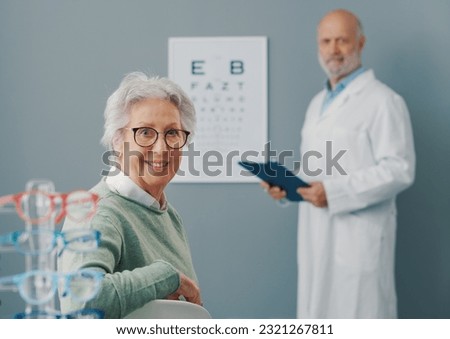 Senior woman having an eye exam with a doctor, they are smiling at camera Royalty-Free Stock Photo #2321267811