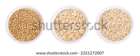 Oat grains, rolled oats and oatmeal, in white bowls. Husked common oat, Avena sativa, a cereal grain. Dehusked steamed oat groats, rolled into flat flakes, toasted, used whole or as steel-cut flakes. Royalty-Free Stock Photo #2321272007