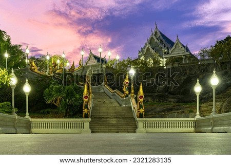 Shot of the temples of Wat Kaeo Korawaram in Krabi, Thailand. White Temple with a blue roof to which stairs lead. Sunset background.