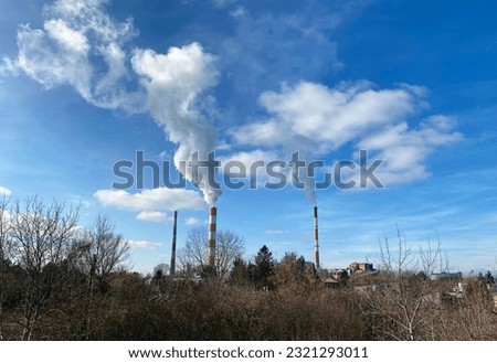 An industrial factory with pipes emitting white smoke into the sky Royalty-Free Stock Photo #2321293011