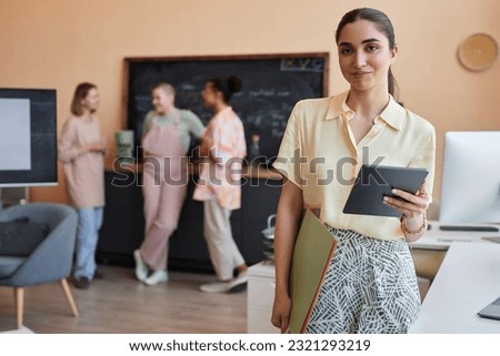 Waist up portrait of Middle Eastern young woman looking at camera standing in modern office setting, copy space Royalty-Free Stock Photo #2321293219