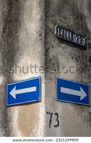 A vertical shot of road signs on a wall showing right and left on Cuban street
