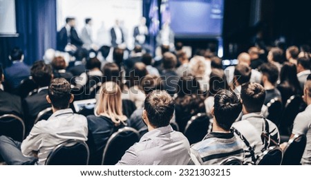 Speaker giving a talk in conference hall at business event. Rear view of unrecognizable people in audience at the conference hall. Business and entrepreneurship concept Royalty-Free Stock Photo #2321303215