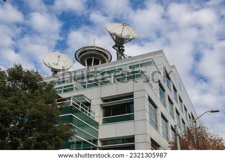Generic office building with vintage satallites and top of space needle with cloudy sky in seattle