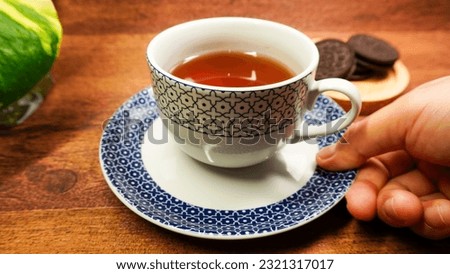 hand holding a cup of tea on wooden table, woman hand holding a mug of tea, hot tea