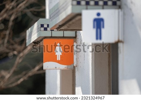 A selective focus shot of ladies and men's restroom signs on old metallic banners
