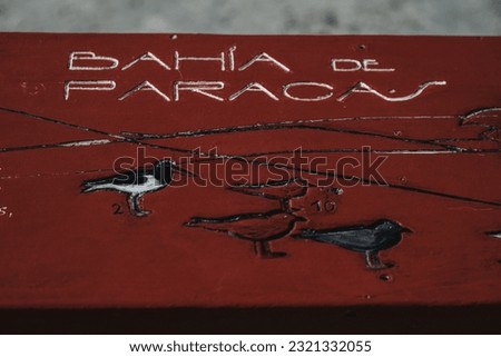 A close-up of a red wooden sign with an inscription and picture of birds