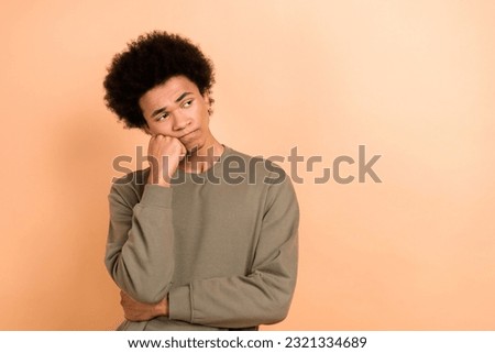 Photo of minded unsatisfied young man hand touch cheek look empty space isolated on beige color background Royalty-Free Stock Photo #2321334689