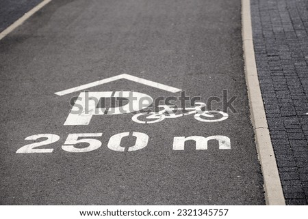 A white bicycle path sign on an asphalt road outdoors