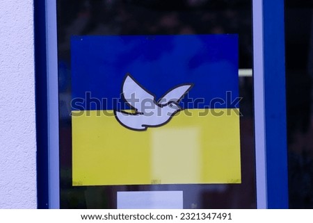 A close-up shot of a peace pigeon symbol on a flag of Ukraine on a glass window.