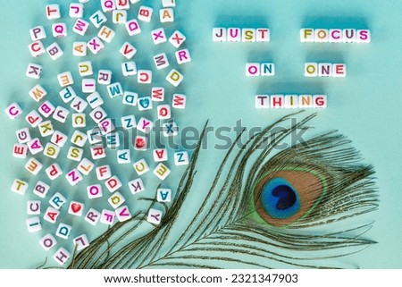 Flat lay on baby blue background with phrase Just focus on one thing made out of square beads. High quality photo.