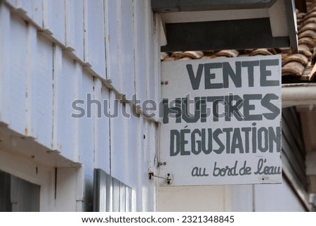 A sign with a text, translation: sale oysters tasting at the edge of the water