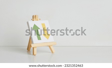 An easel displaying a large arrow symbol on a plain white background