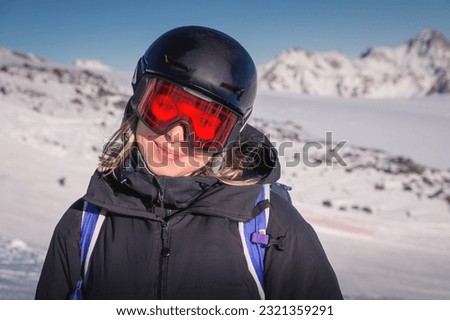 Woman skier on the slope of a mountain resort. Portrait of a young woman smiling in ski equipment, goggles and a helmet