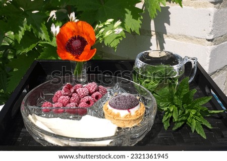 Light tasty breakfast snack in summer. Delicious mint tea, frozen raspberry cheese dessert A small bouquet with poppies in the yard near the grapes romantic summer vacation at the hacienda