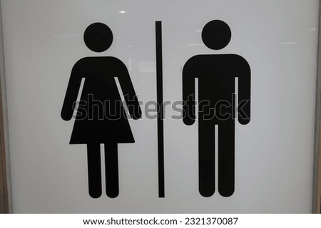 A closeup of male and female toilet signs on a white door of Airport Sevilla, Spain