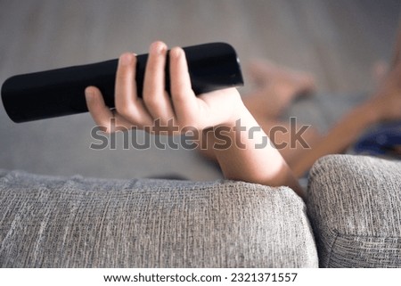 Boy leaning on armchair using tv remote control