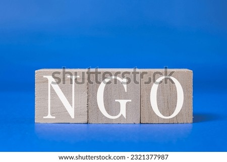 A technical term of NGO on wooden cubes on blue background, Non-governmental Organization, Nobody