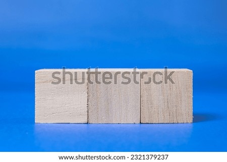Three wooden cubes on blue background, Editable image