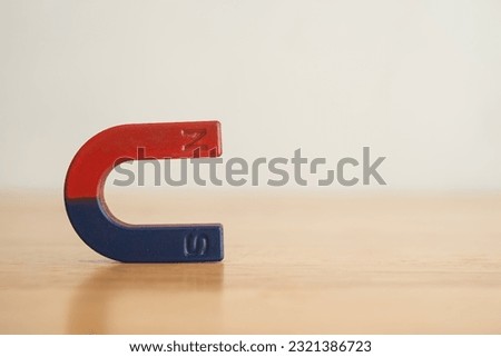Simple horseshoe magnet on wooden table with white wall background copy space. Science or abstract of business, hr human resources, financial, investment and education concept.