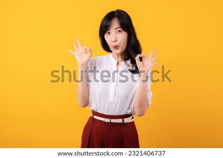 Portrait young beautiful asian woman enterpriser happy smile wearing white shirt and red plants showing okay sign hands gesture isolated on yellow background.