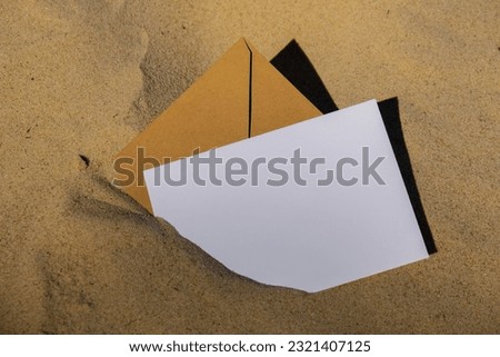 Beige natural tones Envelope with empty white paper note copy space for your text in the sand at the beach. Card mock-up and craft envelope Summer still life scene. Sandy beach background or desert