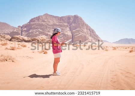 Young caucasian woman are lost and looking at a map.Girl Hiker alone in wadi rum desert looking at map for guidance in lost of her way
