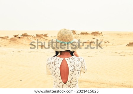 Female tourist visit sit on bench take photo of Fossil Dunes Structures. Abu Dhabi, UAE. Famous travel destination outside capitsl
