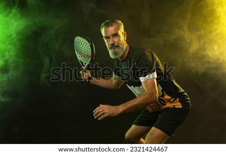 The old man. Padel tennis player with racket. Man athlete with paddle racket on court with neon colors. Sport concept. Download a high quality photo for the design of a sports app or betting site.