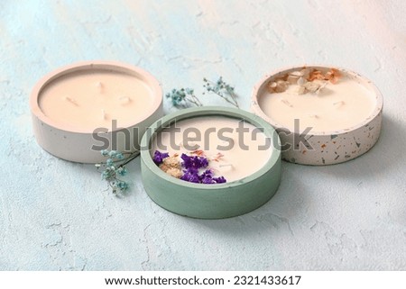 Holders with candles and flowers on blue background