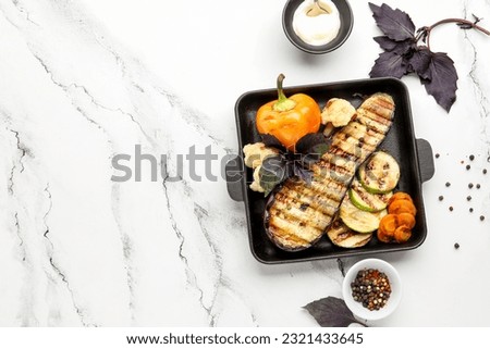 Baking dish with grilled vegetables and basil on white background