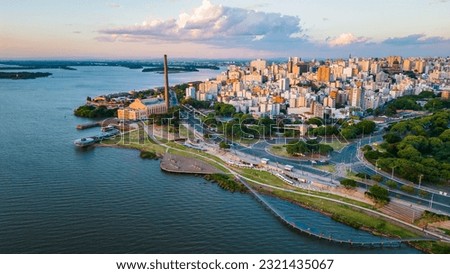 Aerial Drone Fly Above Beautiful Cityscape of Porto Alegre Brazil Neighborhood Gasometro, Guaiba Lake, Architecture and Road Traffic with Warm Skyline Royalty-Free Stock Photo #2321435067