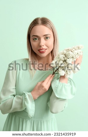 Young woman with lilac flowers on green background