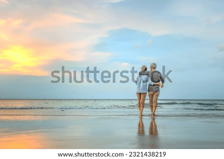 Plan life insurance of happy retirement concepts. Senior couple walking on the beach holding hands at beach sunrise in evening. Royalty-Free Stock Photo #2321438219