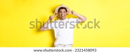 Concept of tourism and vacation. Happy man tourist posing for photo with peace signs, smiling excited, standing against yellow background.