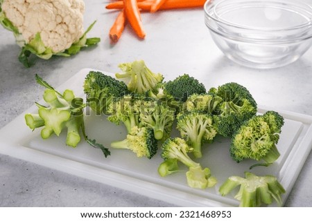 Broccoli florets close-up. Fresh raw organic broccoli on a white cutting board on kitchen table, still life, cooking process, recipe Royalty-Free Stock Photo #2321468953
