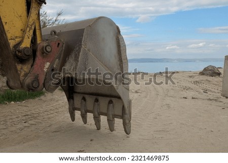 Excavator bucket on the background of the beach and the sea