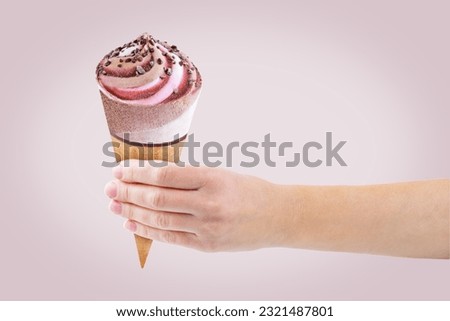 Hand with chocolate berry vanilla ice cream in waffles cone on a brown background. toning. selective focus