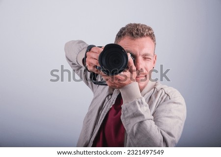 A photographer takes a photograph with his DSLR, studio shot with a white background